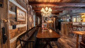 A rustic wooden interior with a long dining table, benches, and a chandelier. - Uncle Tom's 3BDR Cabin For Nature Lover (Grayling)