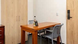 Une petite pièce avec une table en bois et deux chaises, une armoire en bois et une porte dotée d’une poignée.