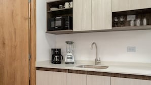 Une cuisine dotée de meubles en bois, d’un four à micro-ondes, d’une machine à café, d’un mixeur et d’un évier.