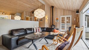 Een moderne woonkamer met een leren bank, een ronde salontafel en houten stoelen.