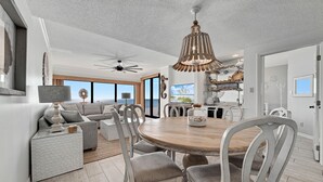 Un salón amplio con una mesa de comedor de madera, sillas grises tapizadas y un ventilador de techo.