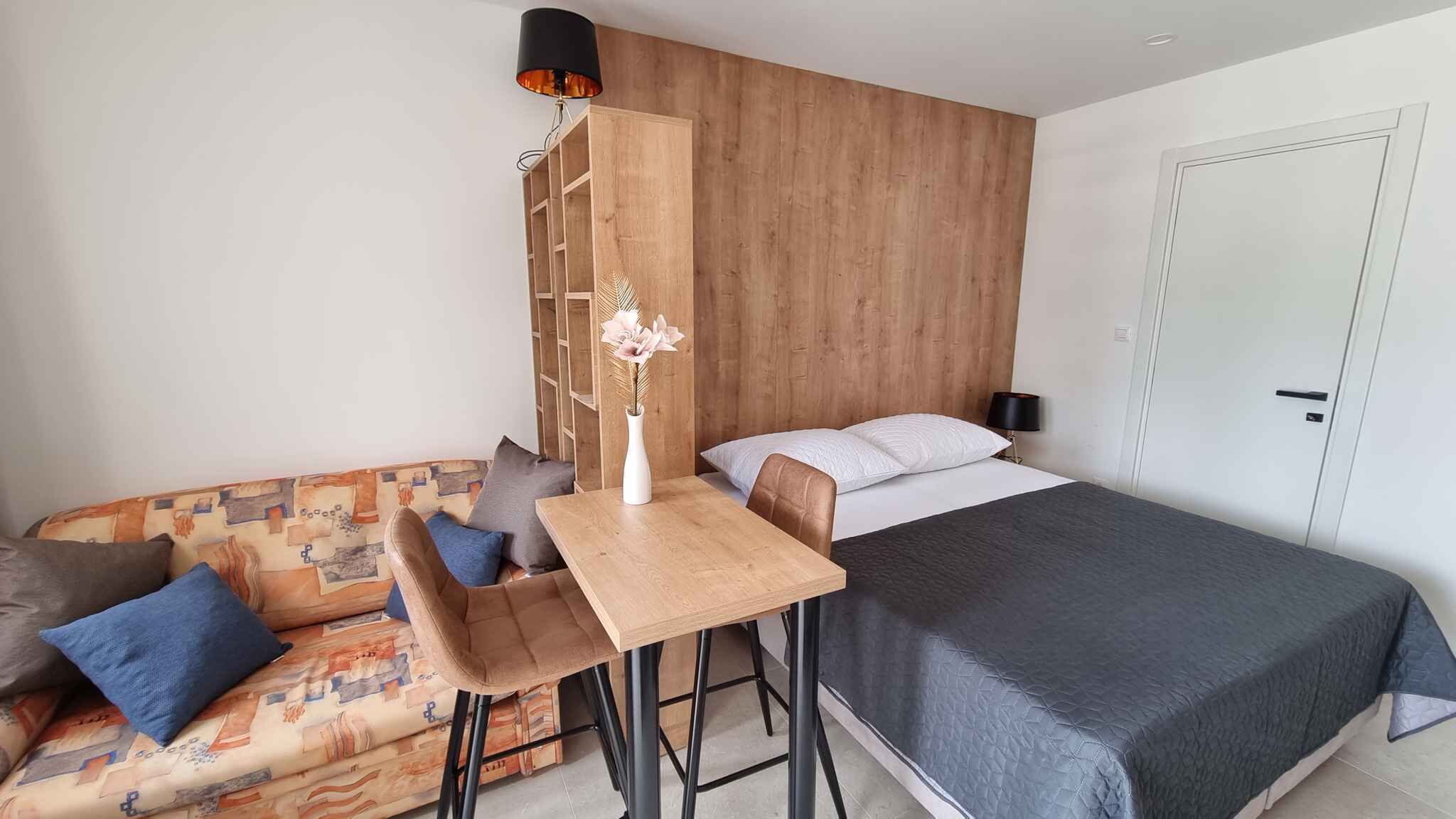 Une chambre d’hôtel de taille réduite, comprenant un lit, une petite table, un canapé et une table de chevet.