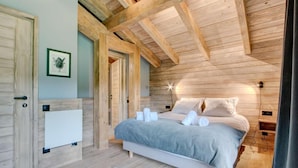 A cozy bedroom with a wooden ceiling, a bed with white linens, and a framed picture on the wall. - Chalet, fitness, swimming pool, sauna, fireplace or stove, parking, tv, 250m², Morzine (Morzine)