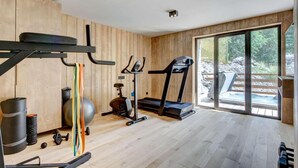 A gym with wooden walls, a treadmill, an elliptical, and a pull-up bar. - Chalet, fitness, swimming pool, sauna, fireplace or stove, parking, tv, 250m², Morzine (Morzine)