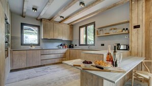 A modern kitchen with wooden cabinets, a marble countertop, and a built-in wine cooler. - Chalet, fitness, swimming pool, sauna, fireplace or stove, parking, tv, 250m², Morzine (Morzine)
