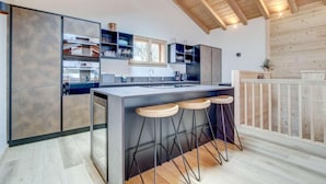 Een moderne keuken met een centraal eiland, barkrukken en inbouwplanken.