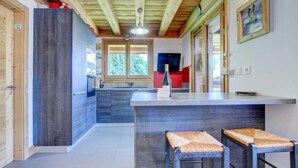 A modern kitchen with wooden beams, a large island, and two bar stools. - 2nd floor, balcony, tv, 60m², Morzine (Morzine)