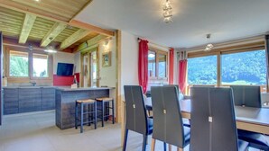 A modern kitchen with a bar area, dining chairs, and large windows offering a view of the outdoors. - 2nd floor, balcony, tv, 60m², Morzine (Morzine)