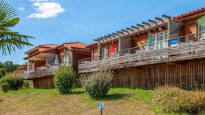 Une rangée de chalets en bois dotés de balcons, un ciel dégagé et un panneau indiquant un parking.