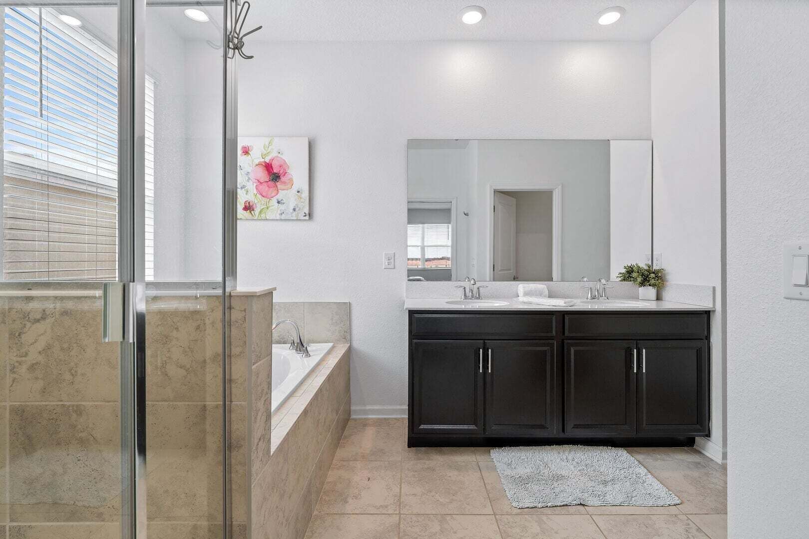 Une salle de bain dotée d’une douche à parois de verre, d’un meuble-lavabo à deux vasques et d’un grand miroir.