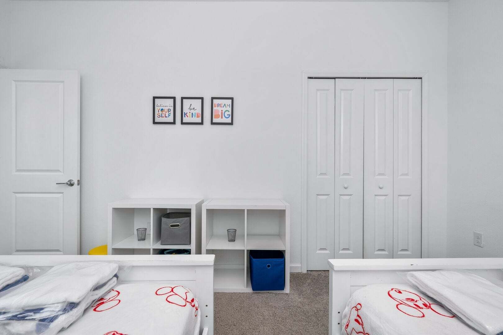 A room with two beds, a wardrobe, and three motivational posters on the wall.