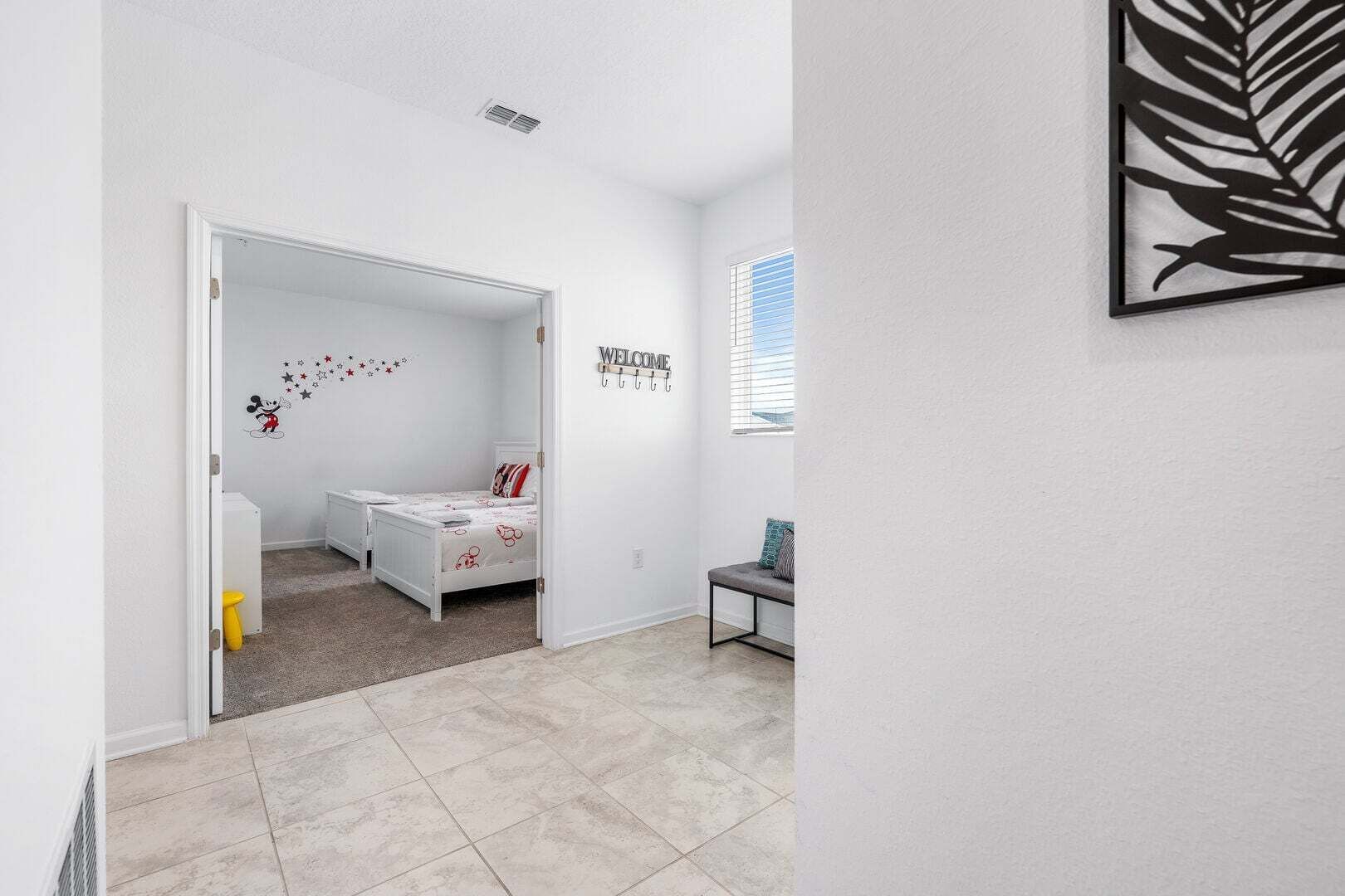 A child's bedroom with a bed, a small table, a chair, and a wall decal.