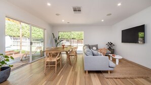 Ein modernes Wohnzimmer mit einem Holzesstisch, einem grauen Sofa und einem an der Wand montierten Fernseher.