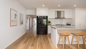 Eine moderne Küche mit einem schwarzen Kühlschrank, weißen Schränken und einem Essbereich aus Holz.