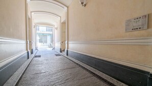 Un couloir avec un sol carrelé, des murs blancs et une porte au fond.