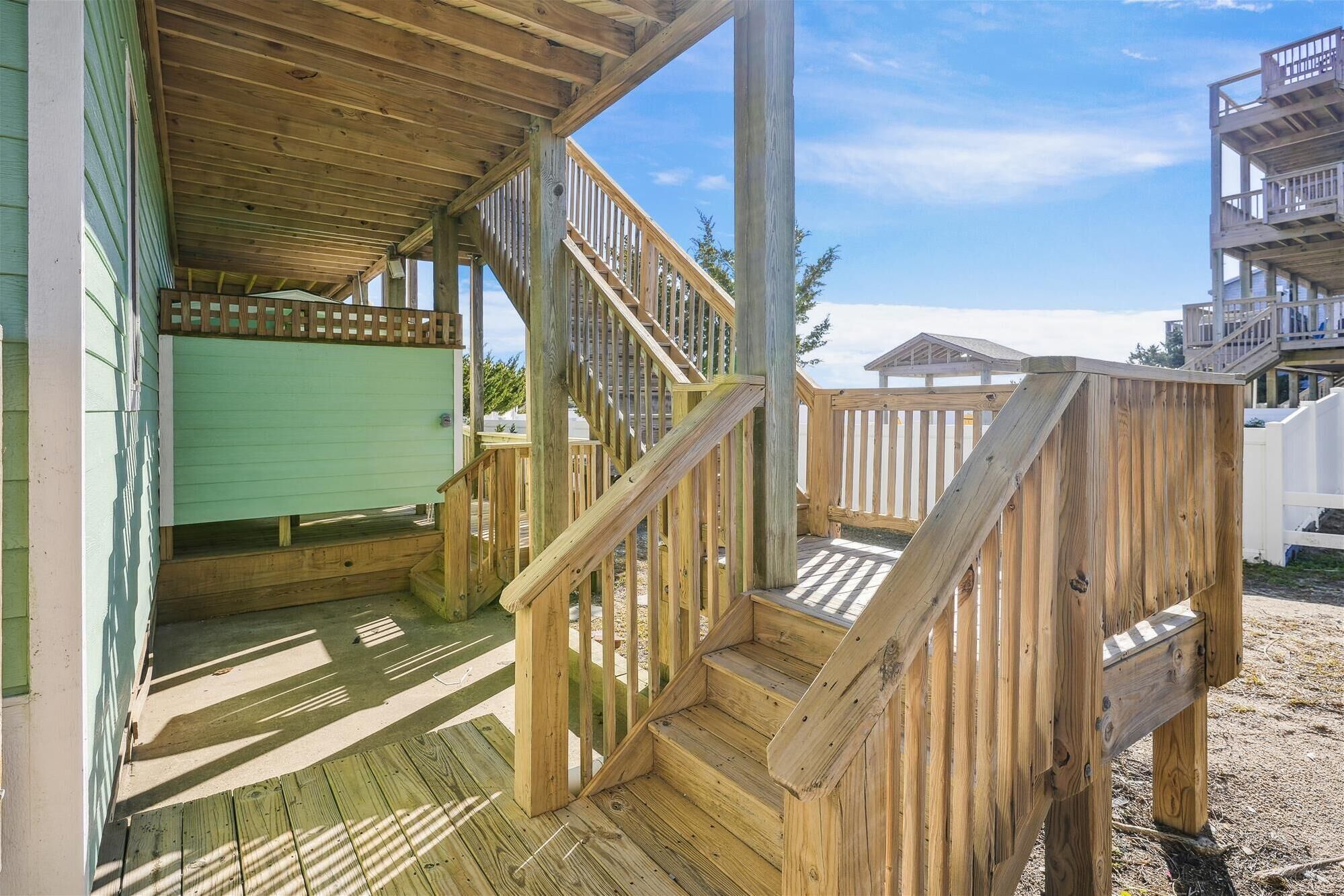 A wooden deck with a staircase leading to a covered area, surrounded by a fence.