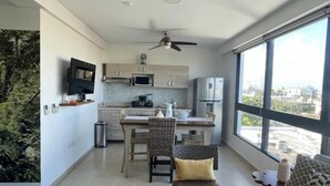 Eine moderne Wohnung mit Küche, Essbereich und Wohnzimmer. Sie verfügt über einen Deckenventilator, ein großes Fenster und einen Blick auf die Stadt.
