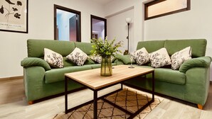 A living room with two green sofas, a wooden coffee table, and a patterned rug.