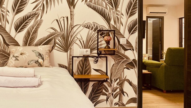A bedroom with a bed, a nightstand, a lamp, and a green chair.