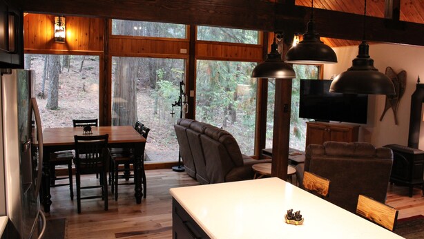 Interior acolhedor de uma cabana com área de jantar, assentos e televisão.