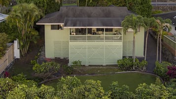 A single-story building with a balcony, surrounded by lush greenery and a small pond.