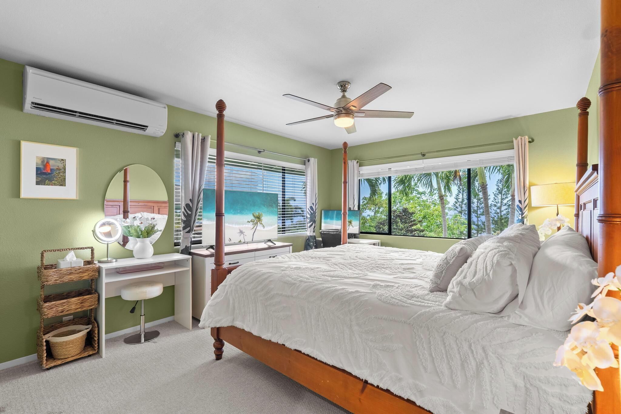 A bedroom with a four-poster bed, a vanity with a mirror, and a desk with a chair.