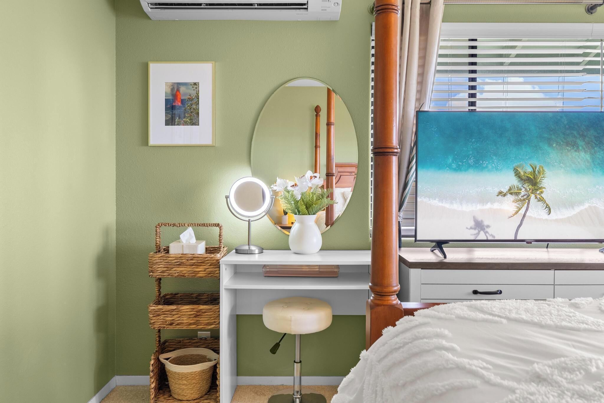 A bedroom with a bed, a vanity with a mirror, a dresser, a wall-mounted air conditioner, and a window with a beach view.