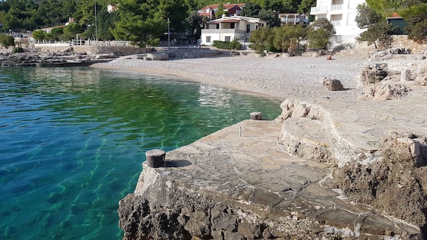A coastal area with clear water, rocky shore, and buildings with red roofs. - Holiday apartment mit Terrasse (Ivan Dolac)