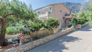 A two-story building with a stone facade, a balcony on the upper floor, and a stone wall surrounding the property. - Holiday apartment mit Terrasse (Ivan Dolac)