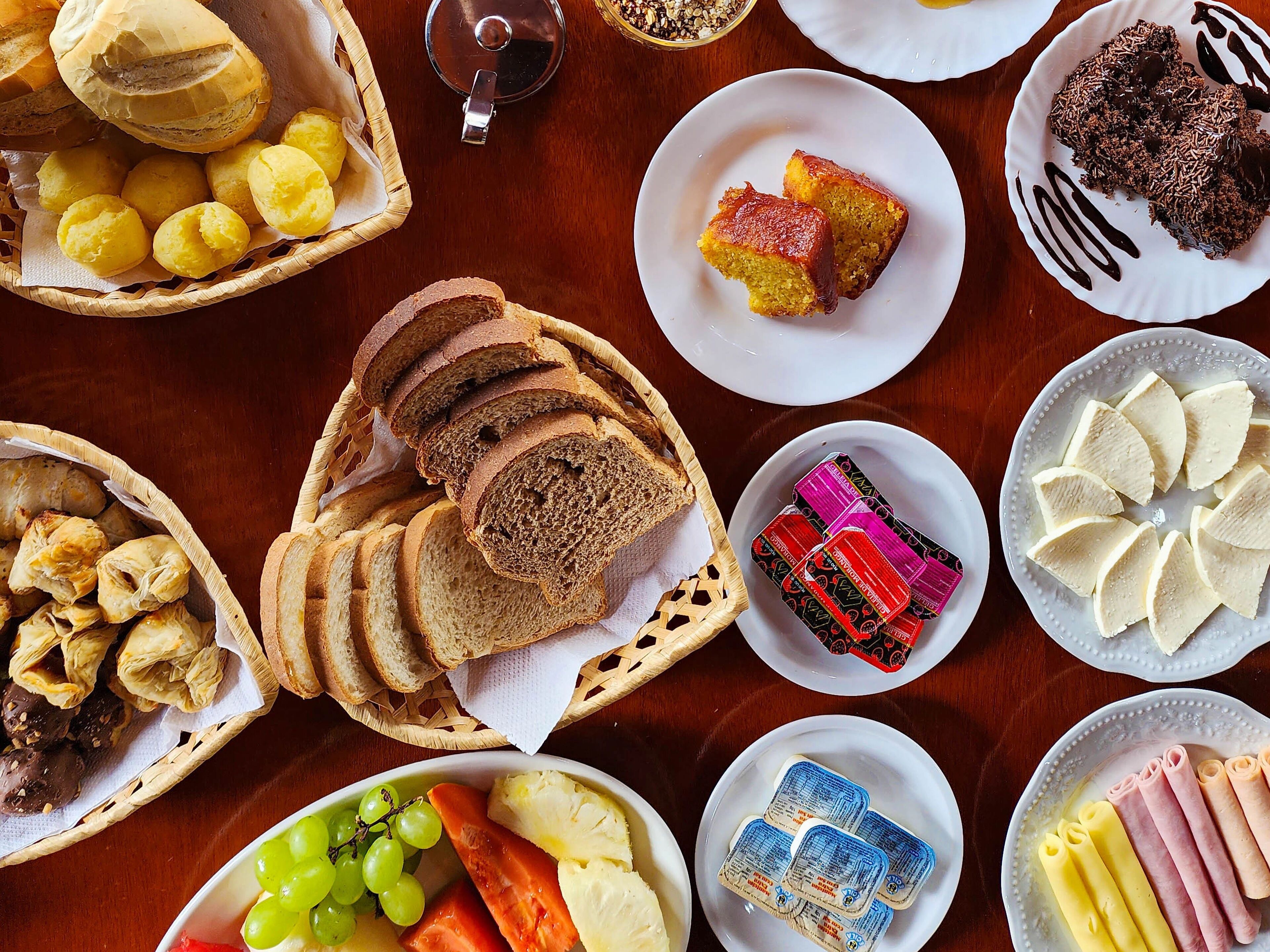Variedad de alimentos como pan, pasteles y queso sobre una mesa.