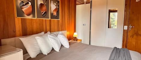 A wooden-paneled room with a bed, a nightstand, and a wardrobe.