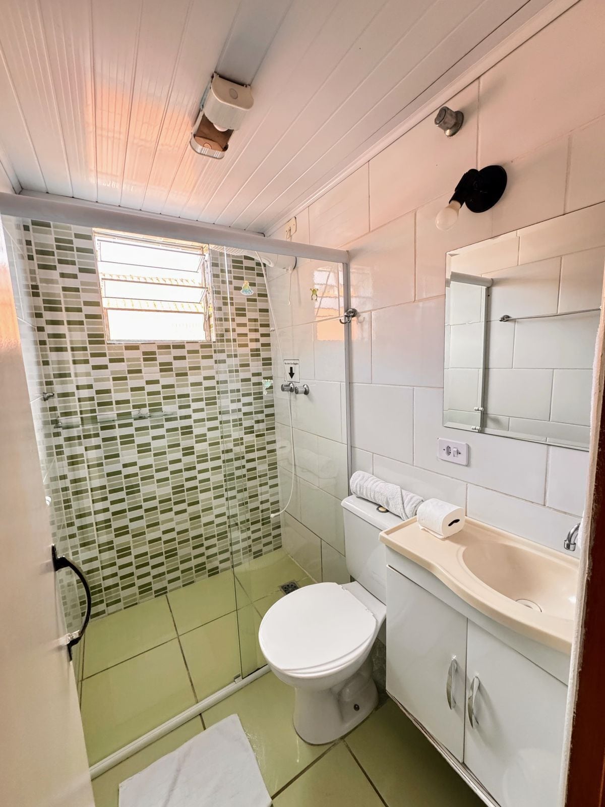 Un baño con ducha, inodoro, lavamanos y espejo.