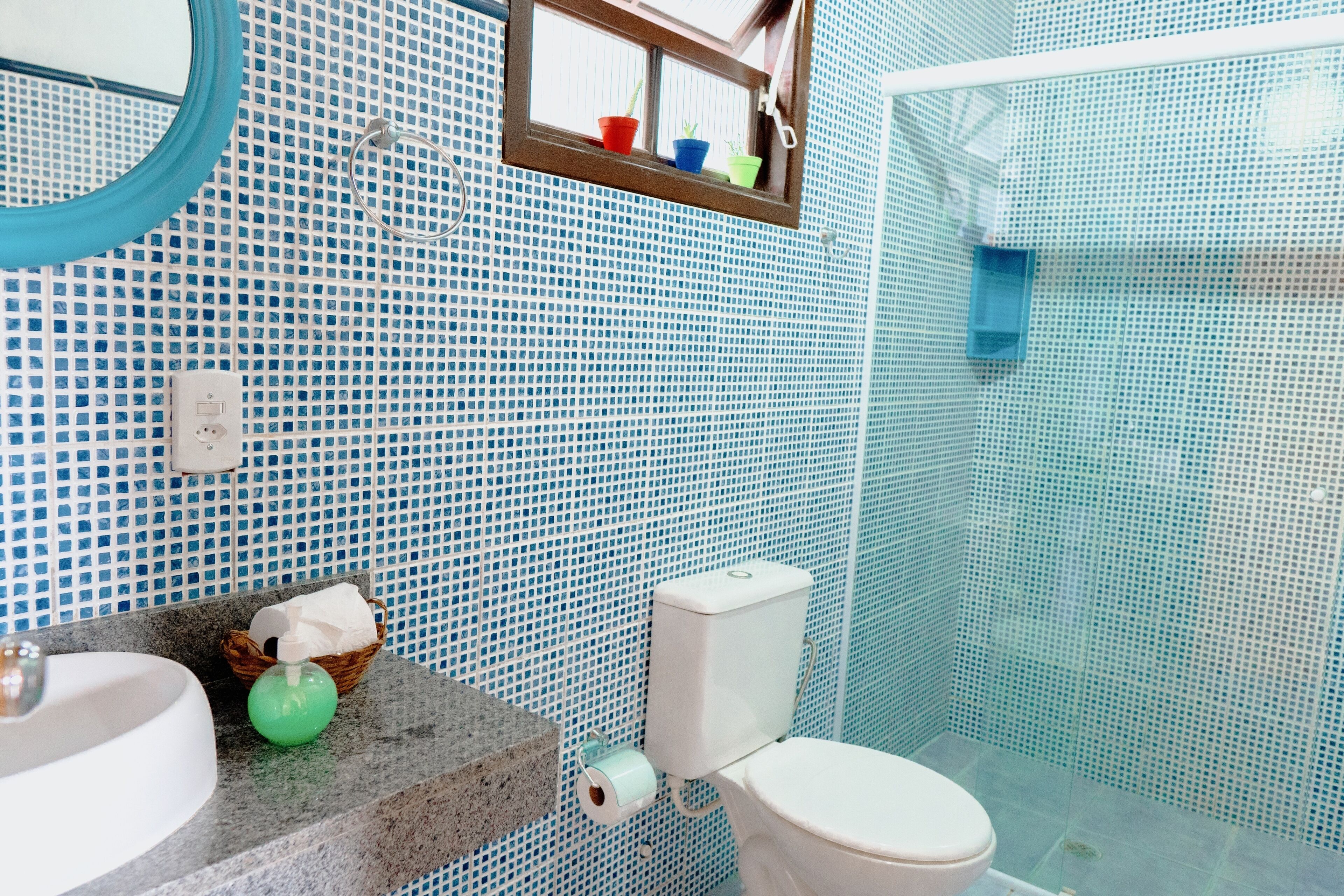 Un baño con pared de azulejos, un lavabo, un inodoro y una zona de ducha.