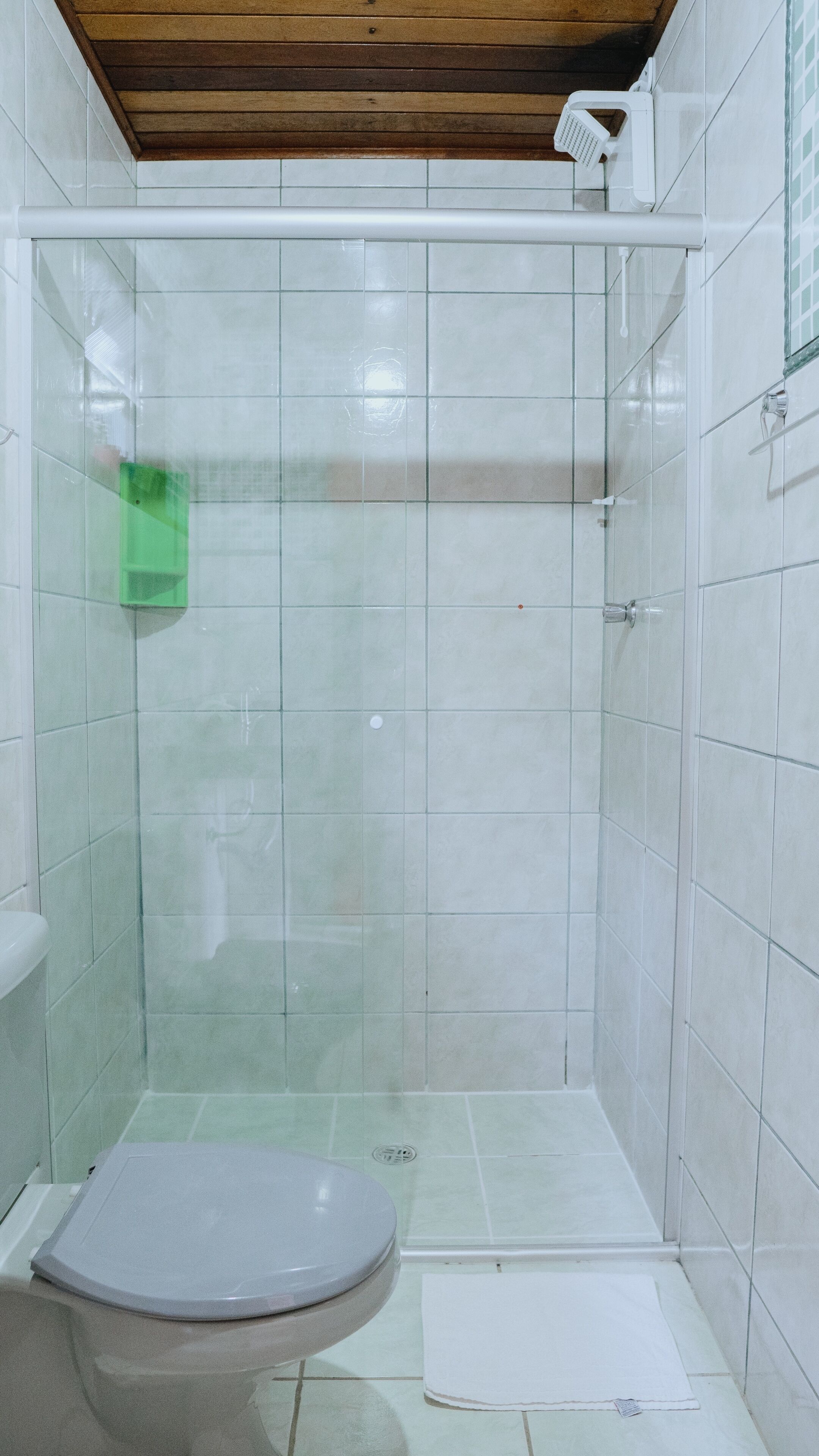 A bathroom with a toilet, a shower area with a glass door, and tiled walls.