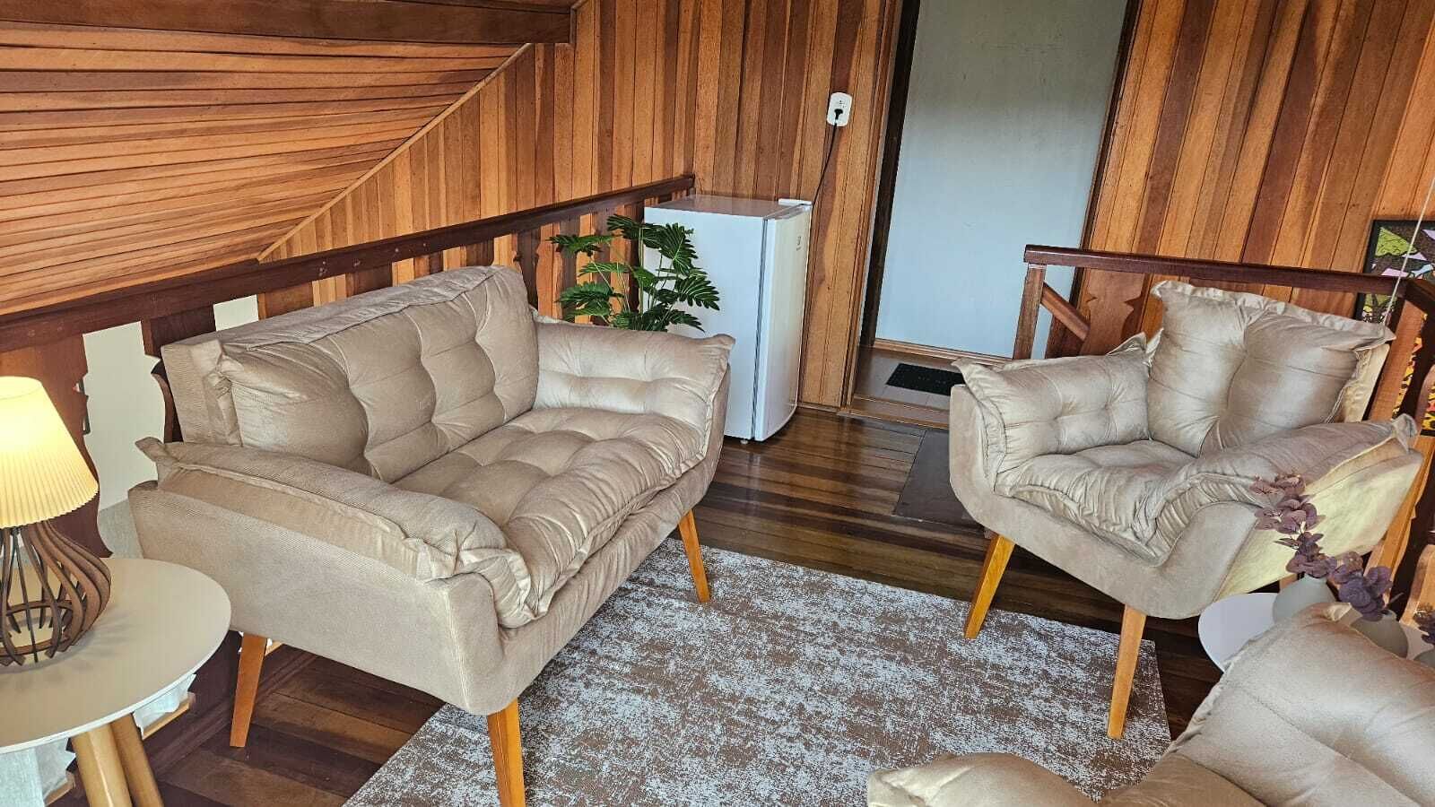 A cozy living room with two beige sofas, a small side table, and a lamp.