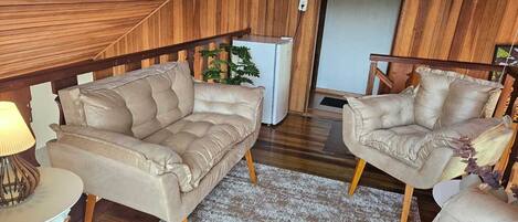 A cozy living room with two beige sofas, a small side table, and a lamp.