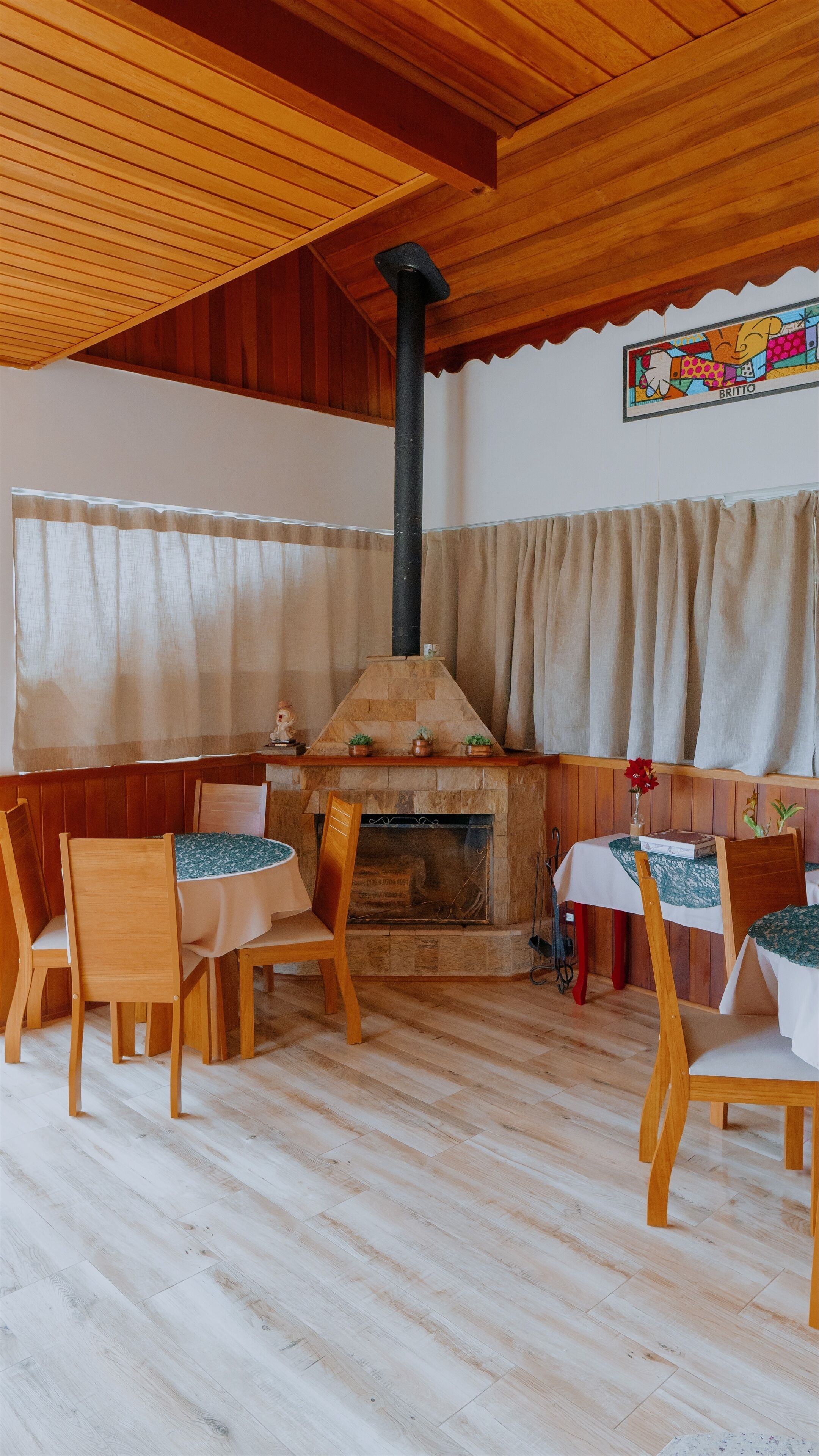 Una habitación acogedora con chimenea de piedra, sillas de madera y una mesa.