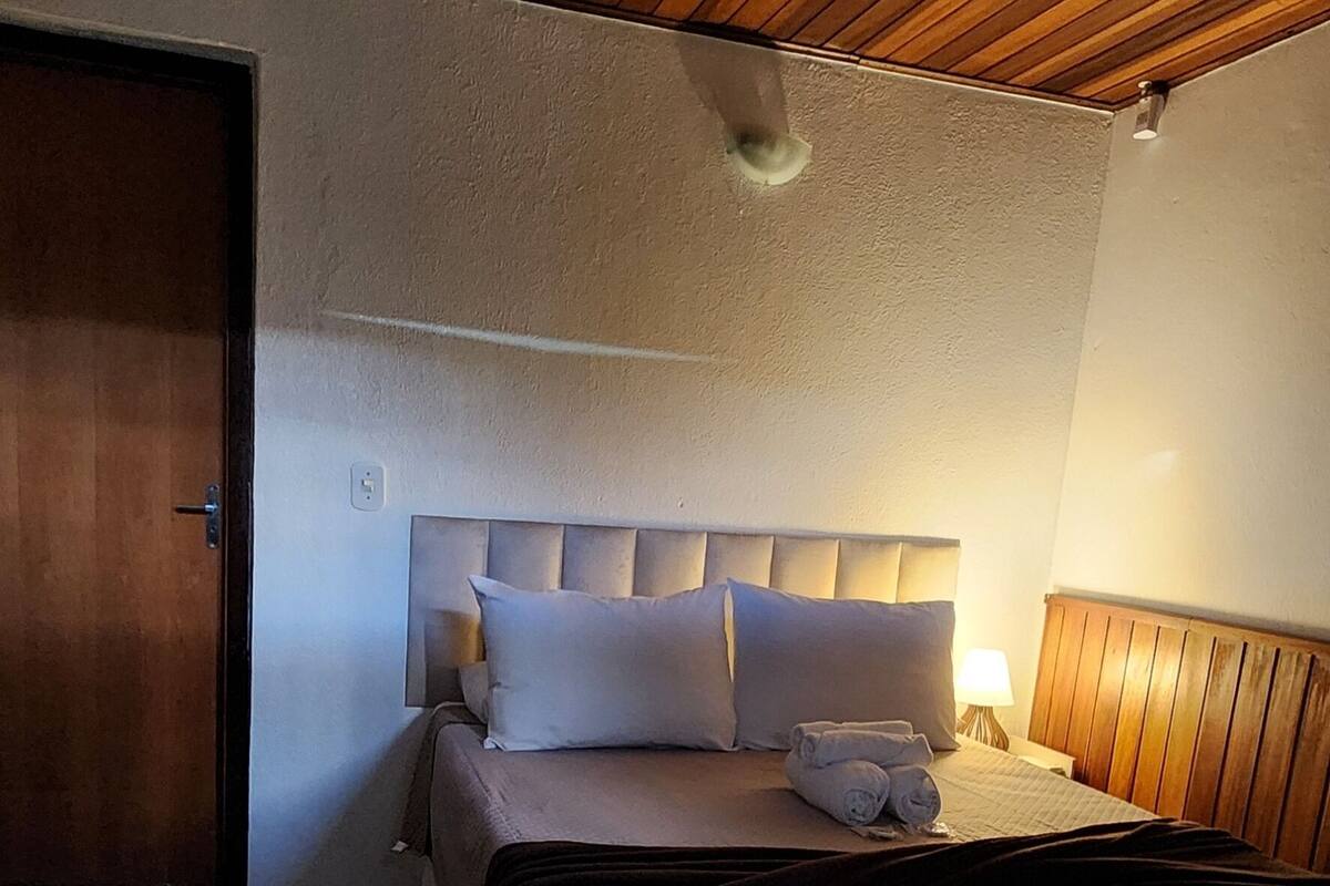 A bedroom with two beds, wooden ceiling, and a fluffy rug.