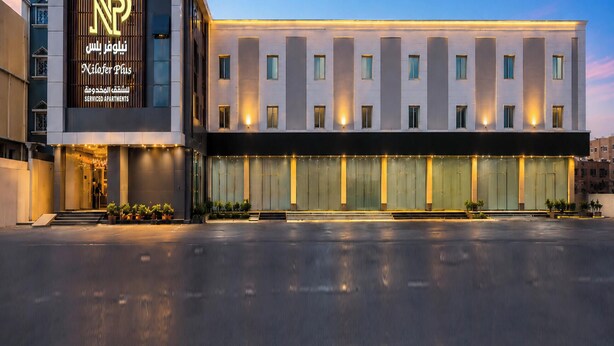 Un edificio moderno con una entrada amplia, un cartel con texto y varias ventanas.