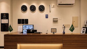 Un mostrador de recepción con relojes, un mapa de servicios y banderas.