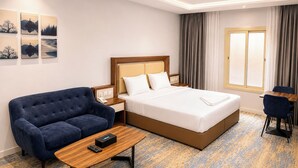 Una habitación de hotel con cama, sofá, escritorio y ventana.