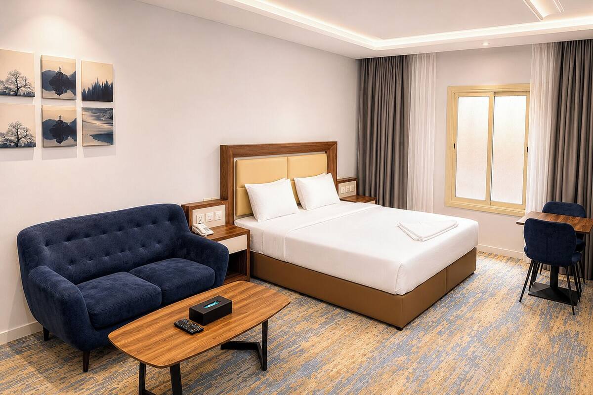 Quarto de hotel com uma cama, um sofá, uma escrivaninha e uma janela.
