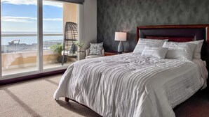 A bedroom with a large bed, a nightstand, a chair, and a view of the ocean. - 5-Star LaJollaReaCondo-Pools&BeachAccess-Rosarito (Rosarito)
