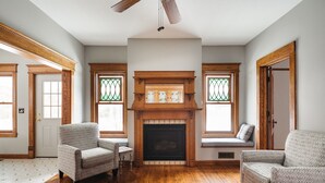A spacious living room with hardwood flooring, two patterned armchairs, a fireplace with a wooden mantel, and a ceiling fan. - 4BDR Broomhead Farmhouse Main House (Williamsburg)