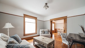 A spacious living room with a wooden coffee table, a sofa, and a dining table with chairs. - 4BDR Broomhead Farmhouse Main House (Williamsburg)