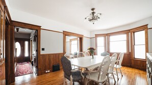 A dining room with a wooden floor, white table, and chairs, a chandelier, and large windows. - 4BDR Broomhead Farmhouse Main House (Williamsburg)