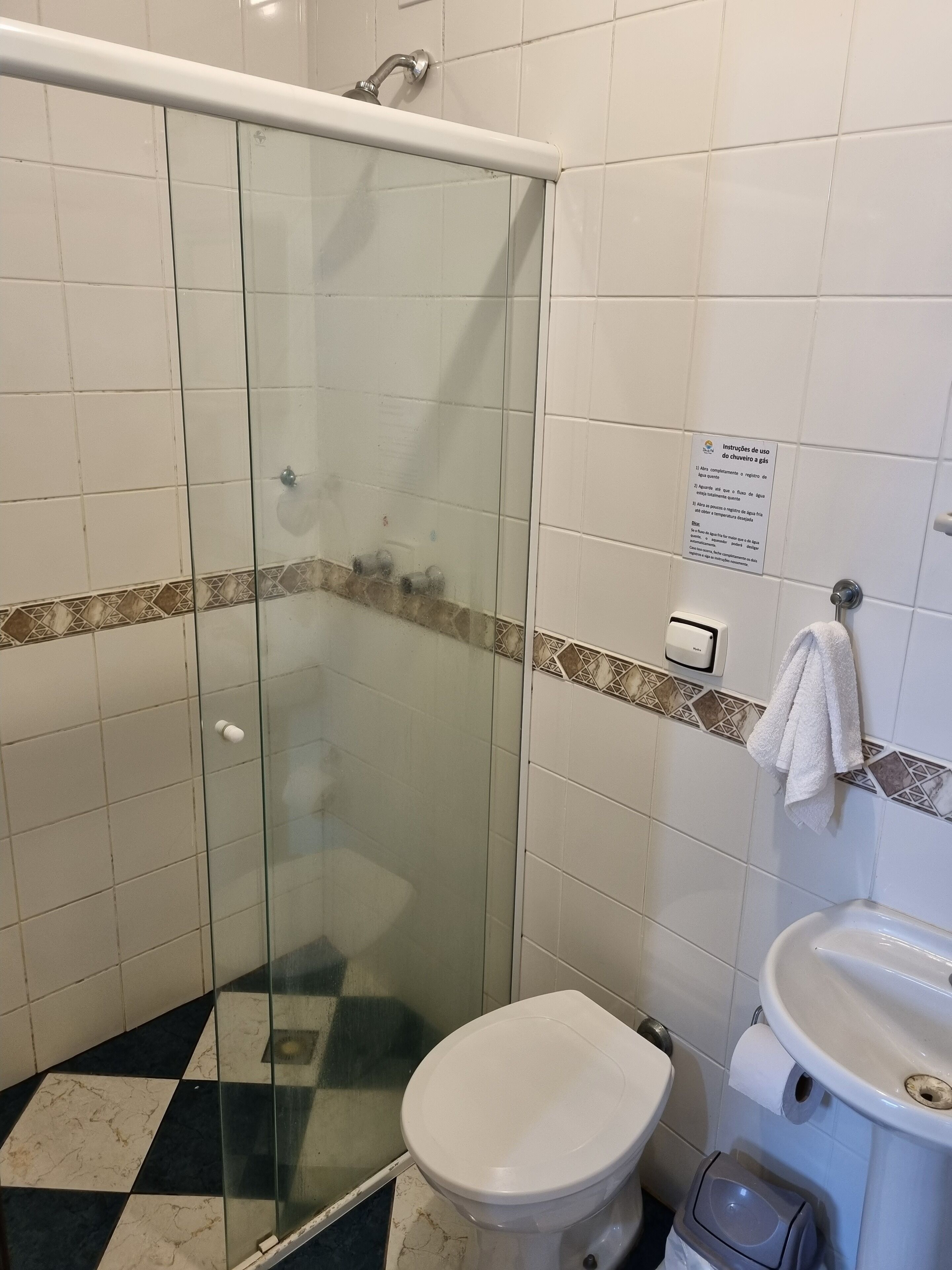 A bathroom with a glass-enclosed shower, a toilet, and a sink.
