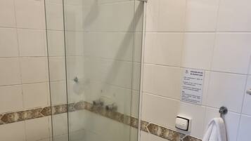 A bathroom with a glass-enclosed shower, a toilet, and a sink.