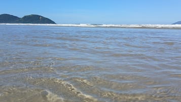 Een strand met helder water en verre eilanden.