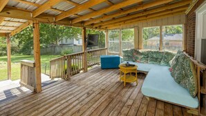A covered porch with a wooden deck, a blue cushioned seating area, and a small table. - Music City House, 4 miles to BDWY, Free Parking (Nashville)